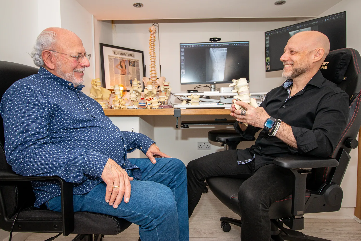 Joel Proskewitz explaining a spinal condition to a patient using a model of the spine